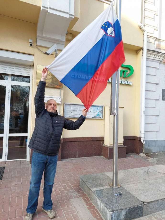 Slovenia&#039;s charge d&#039;affaires at the embassy in Kyiv, Boštjan Lesjak, holding the flag up in the absence of wind