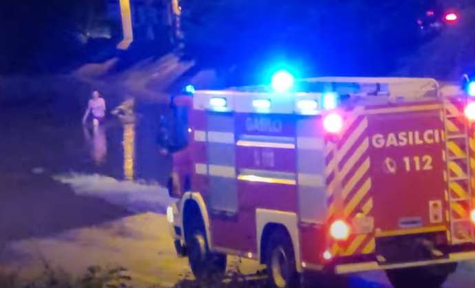 A man explores a flooded area and firefighters intervene