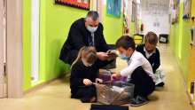 Mr. Walton, the principal, enjoys selecting books from the reading tree with Primary Students